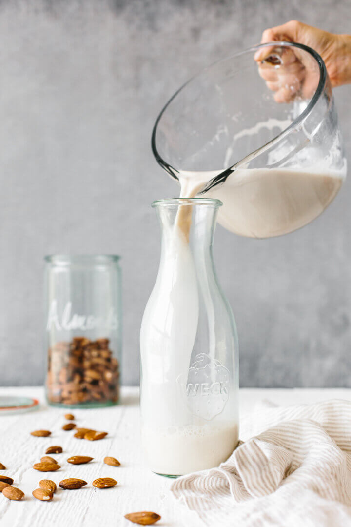 Pouring homemade almond milk into a container