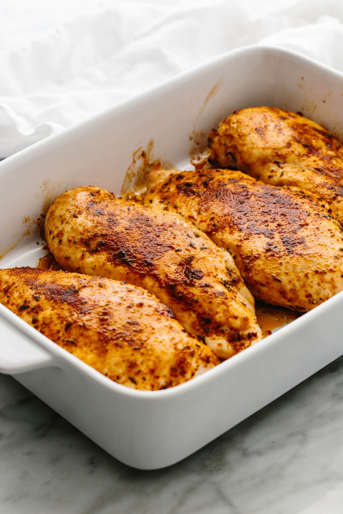 Four chicken breasts in a baking dish.