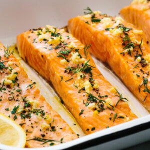Baked salmon fillets in a pan with garlic and herbs.