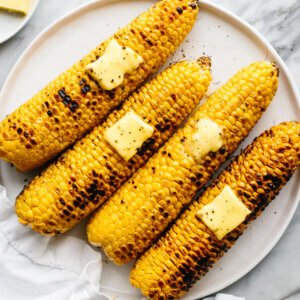 A plate of four grilled corn on the cobs