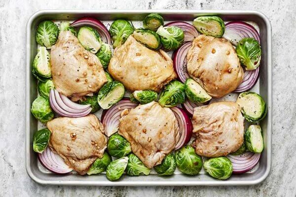 A sheet pan filled with balsamic chicken, Brussels sprouts, and onions