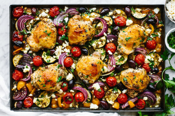 A large sheet pan with Greek chicken and roasted vegetables