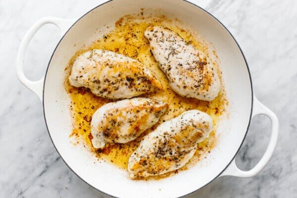 A skillet with seared chicken for tuscan chicken