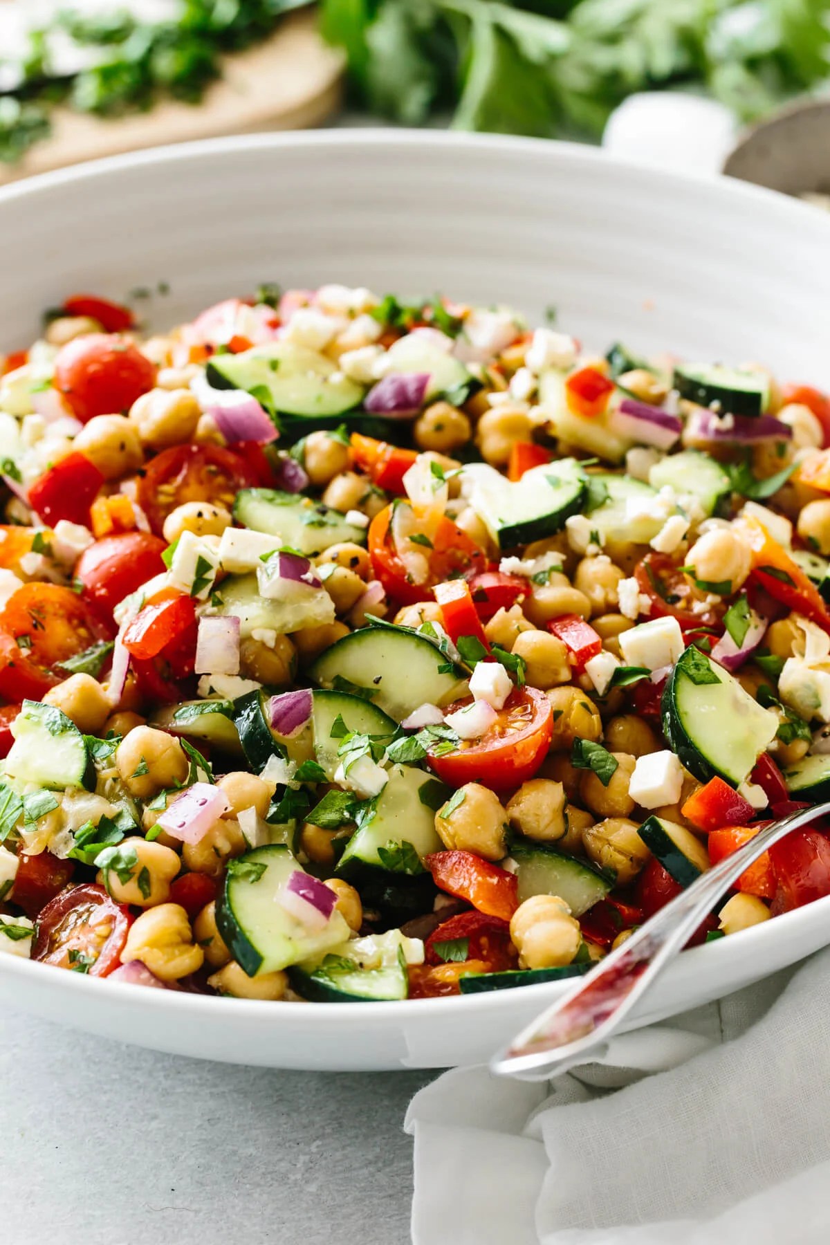 A bowl of Mediterranean chickpea salad with fresh parsley in the background.