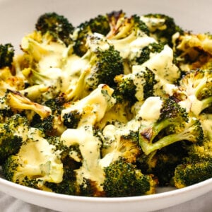 A bowl of roasted broccoli topped with hollandaise sauce.