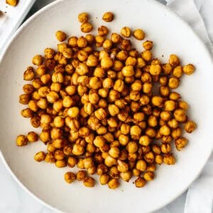 A plate filled with roasted chickpeas next to a napkin