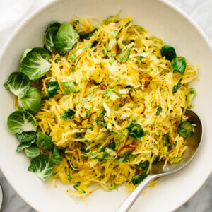 Spaghetti squash, Brussels Sprouts, and Crispy Shallots in a bowl on a table.